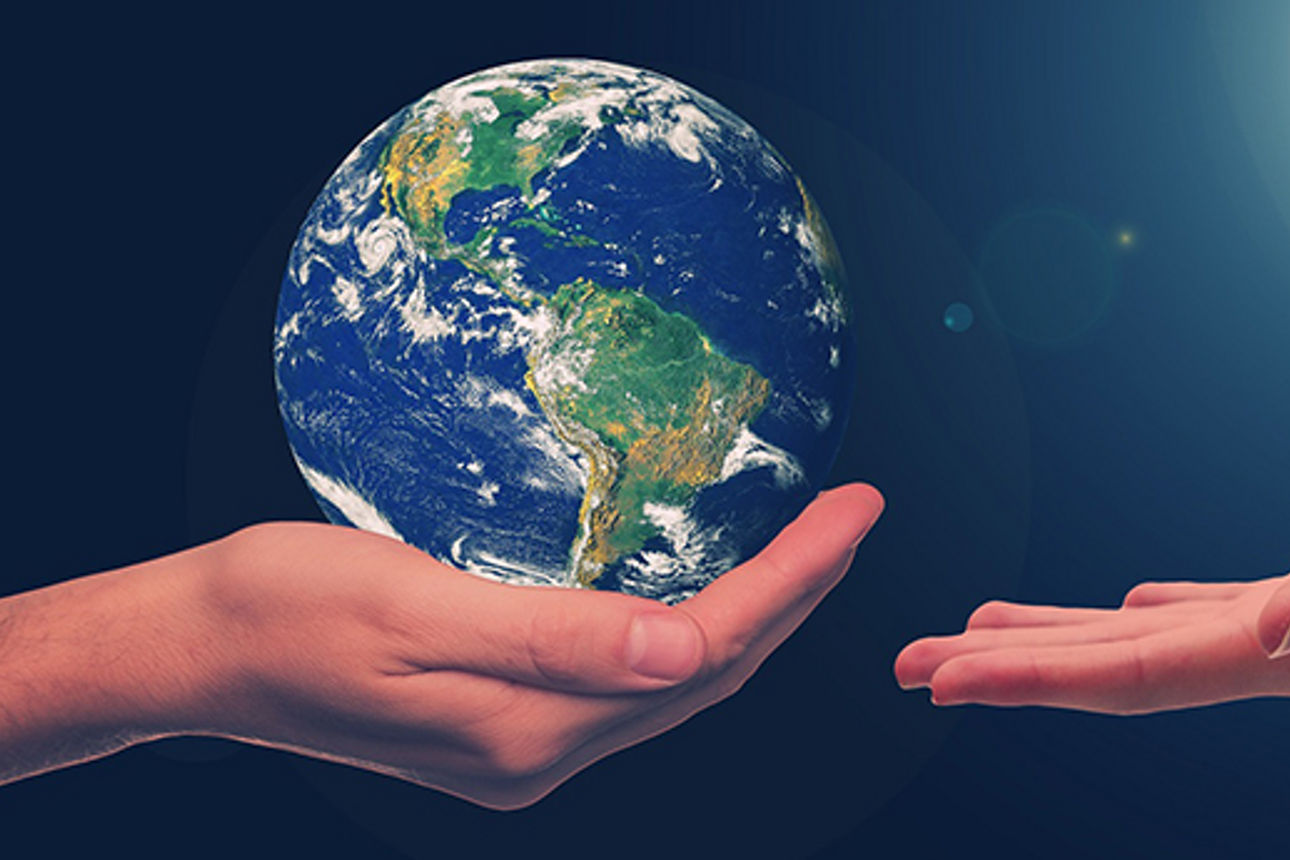 Die eine Hand überreicht der anderen eine Weltkugel