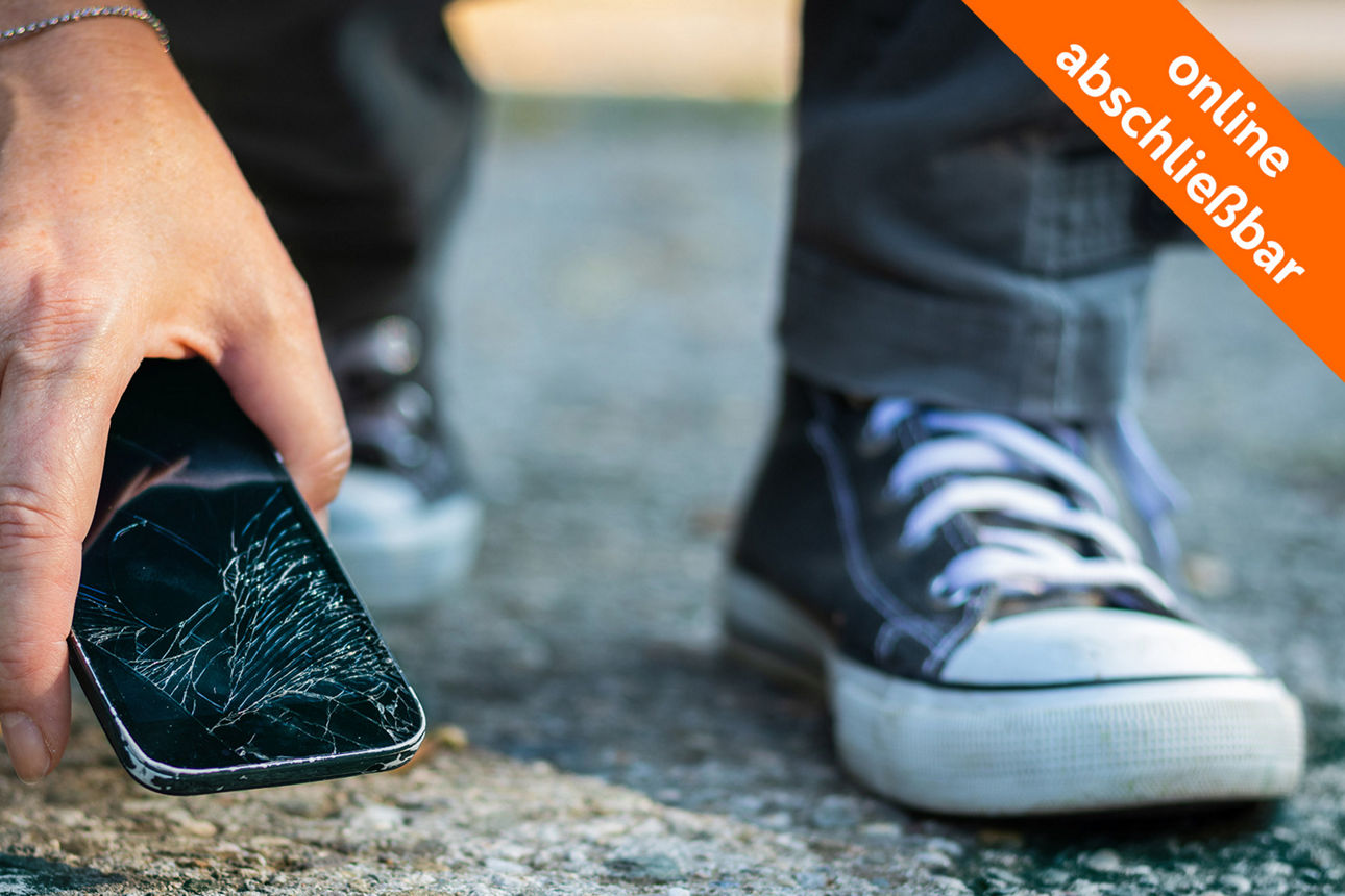 Person hebt zerbrochenes Smartphone auf