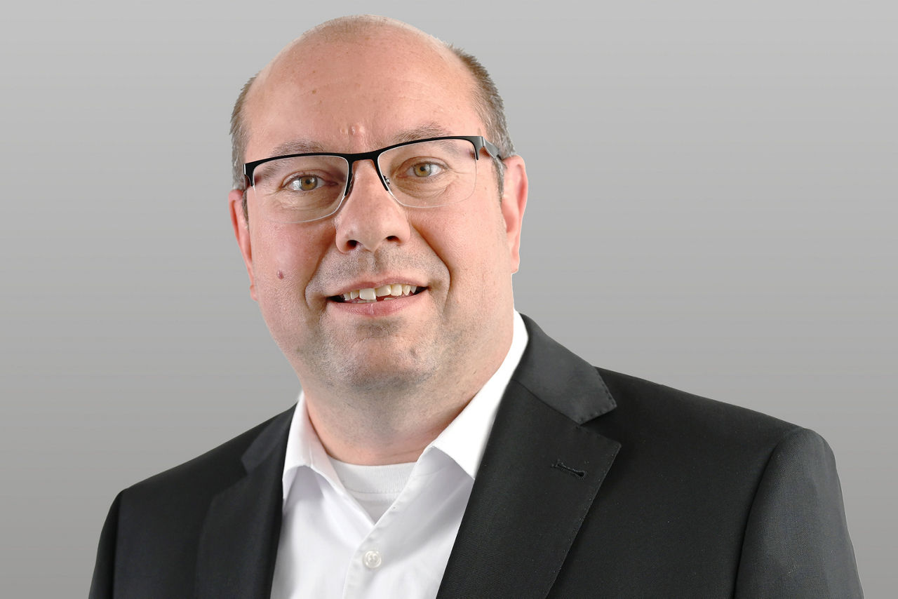 Geschäftskundenberater Marco Hagedorn vor grauem Hintergrund