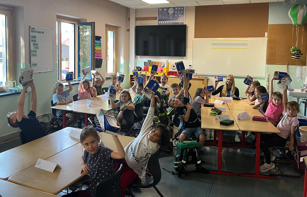 Ein Klassenzimmer voller Kinder, die Bücher lesen, während ein Lehrer sie an der Stirnseite anleitet.