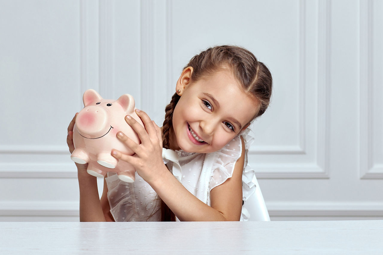 Kleines Mädchen mit Sparschwein zu Hause