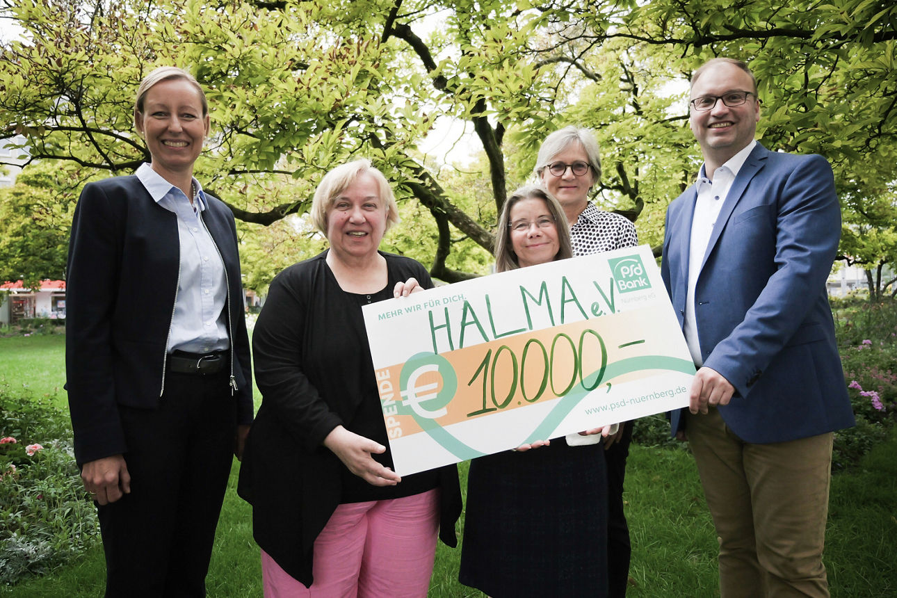 Ein Kollege der PSD Bank Nürnberg übergibt einen Spendencheck an den Halma e.V. Würzburg