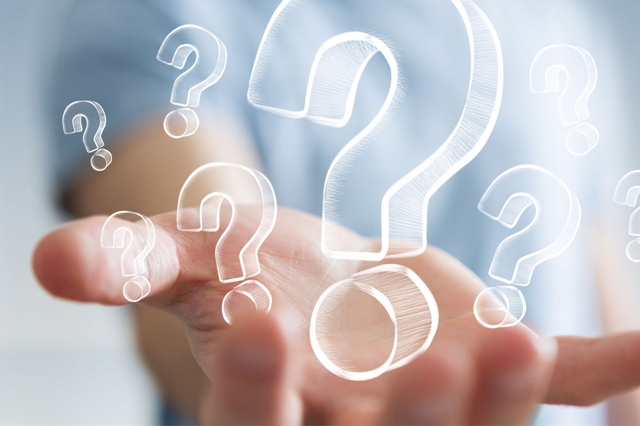 Businessman on blurred background holding hand drawn question marks