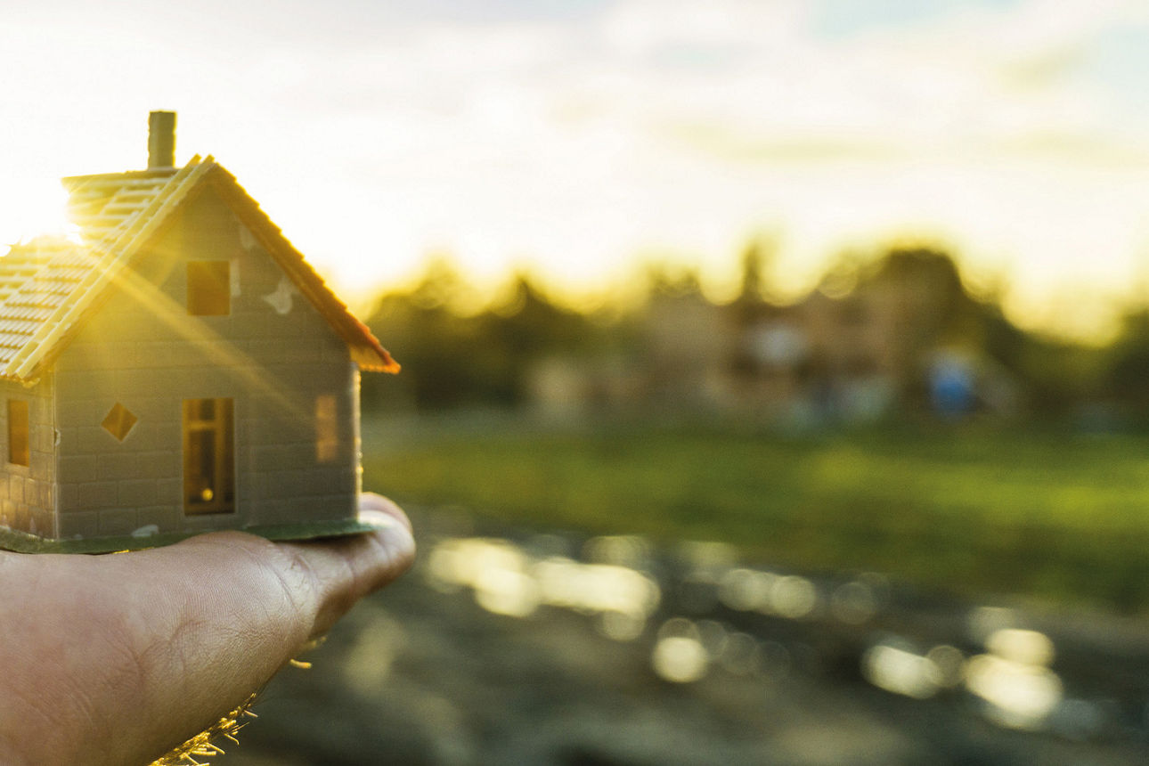 Hand die ein kleines Modellhaus hält