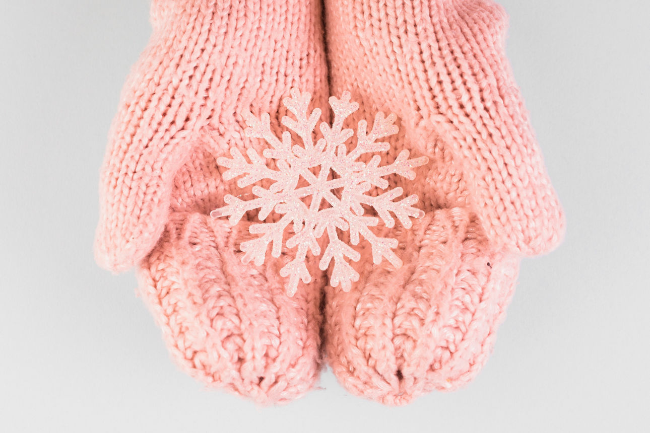 Schneeflocke in Kinderhand mit Handschuhen an