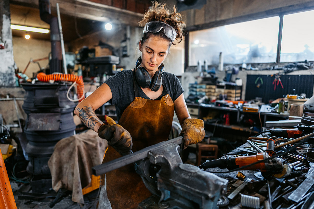Junge Handwerkerin an Maschine macht sich Notizen