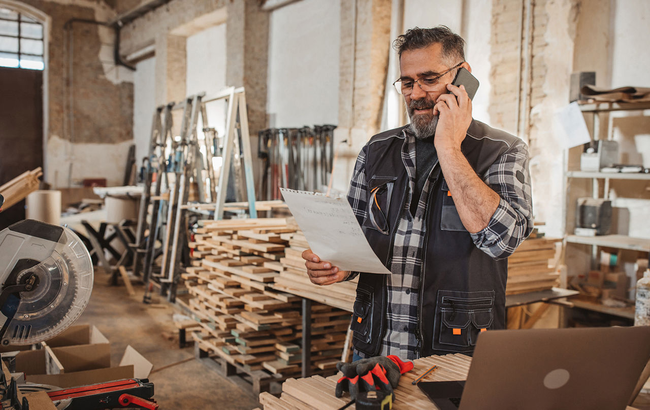 Handwerker telefoniert in einer Werkstatt