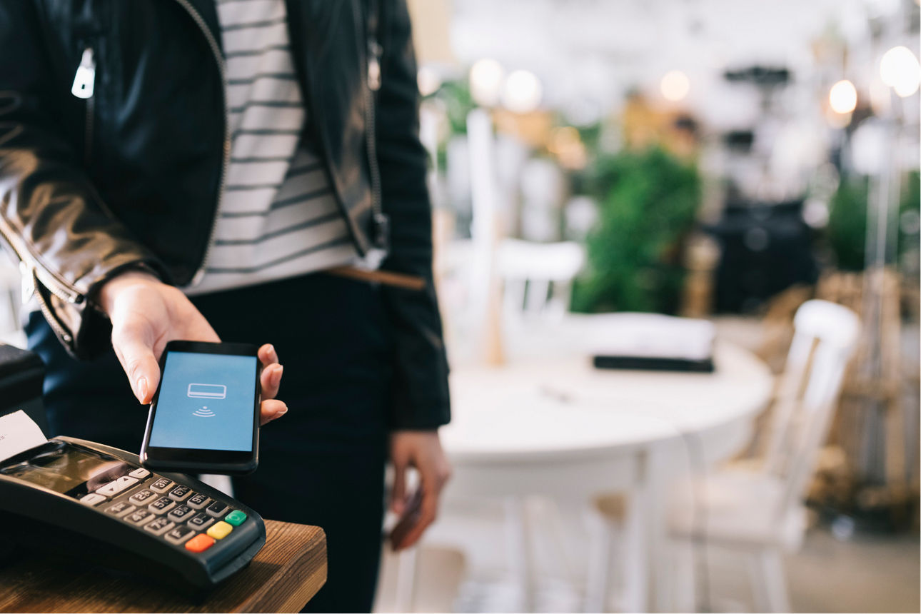 Frau benutz ihr Handy um zu bezahlen