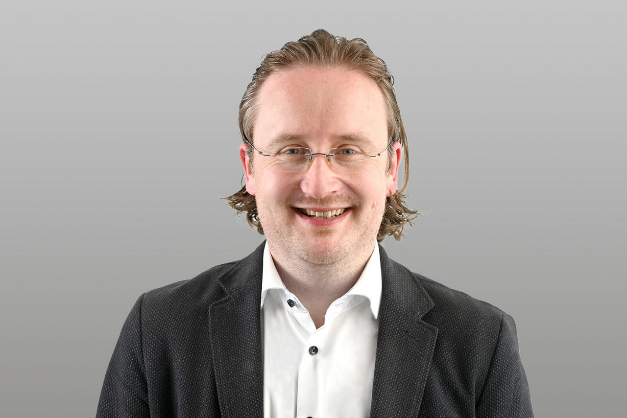 Privatkundenberater Florian Happel vor grauen Hintergrund