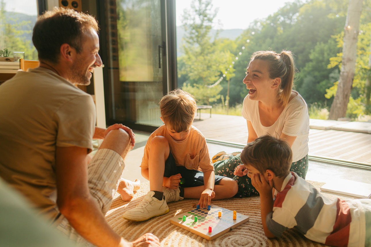glückliche Eltern sitzen mit ihren zwei Kindern und spielen ein Brettspiel