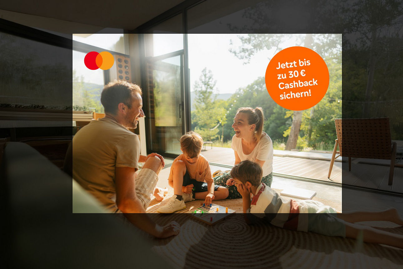 Junge Eltern sitzen mit ihren 2 Söhnen auf dem Boden und spielen Mensch ärgere dich nicht