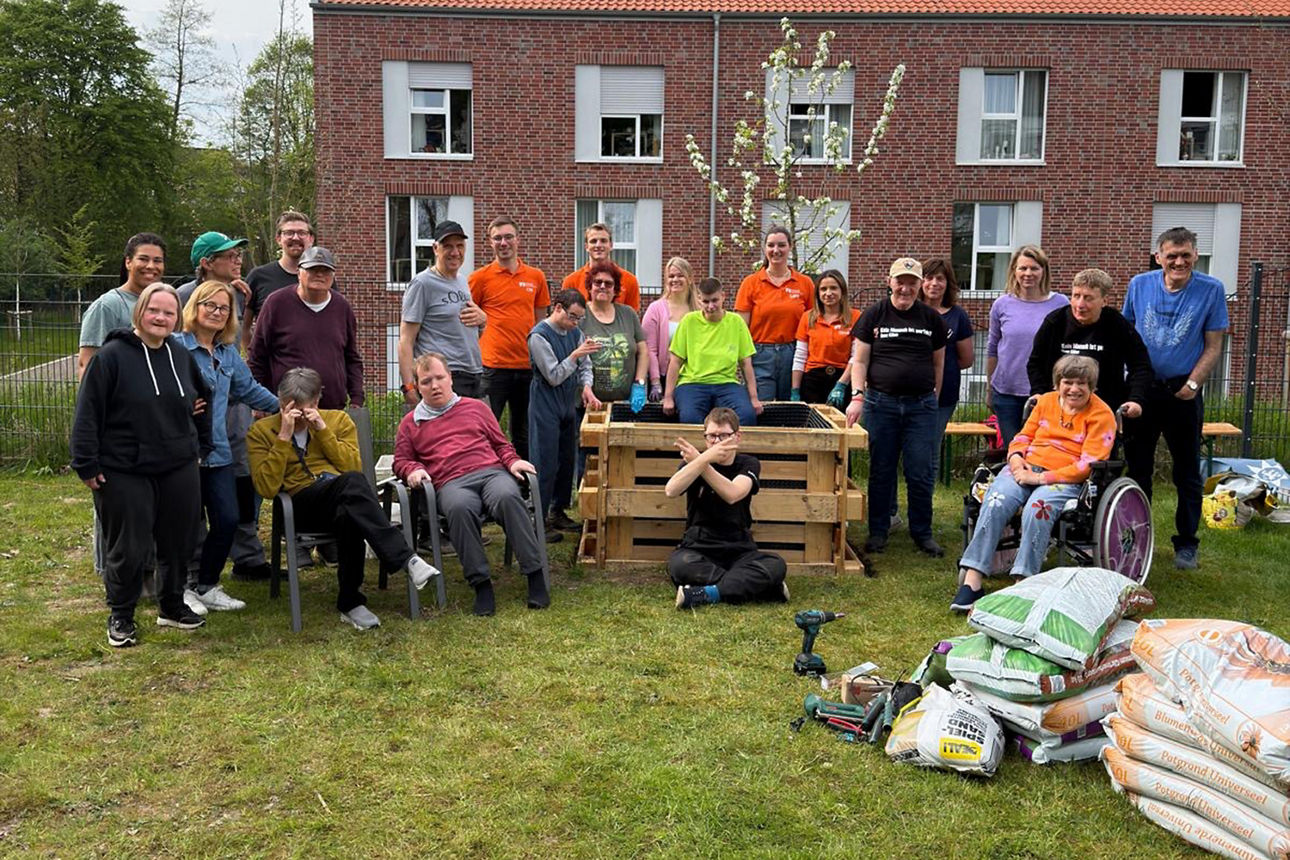 Das Team Rent a Banker der Volksbank Schermbeck und die Bewohner Haus Kilian haben sich zu einem Gruppenfoto um das Hochbeet gestellt.
