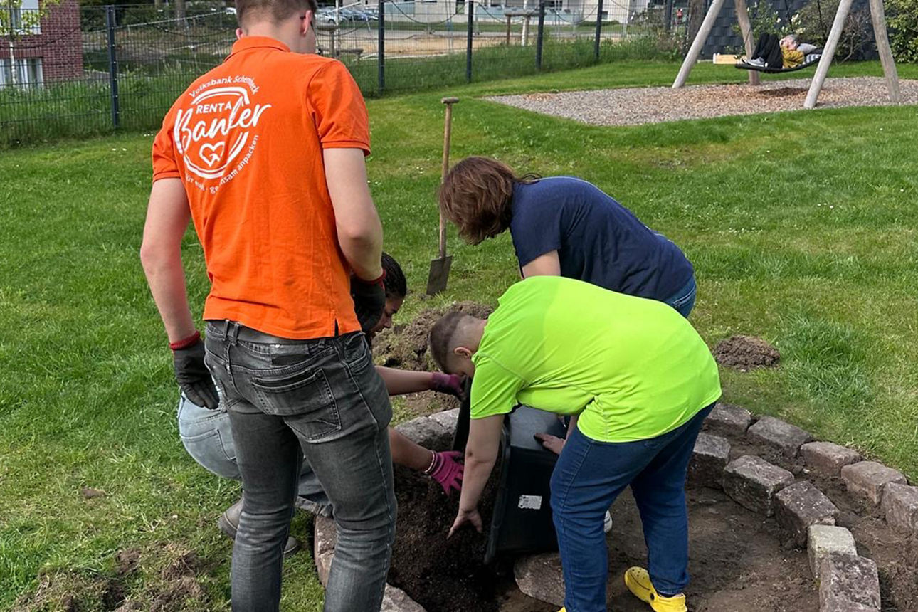 Vier Personen setzten Randsteine für eine Kräuterschnecke