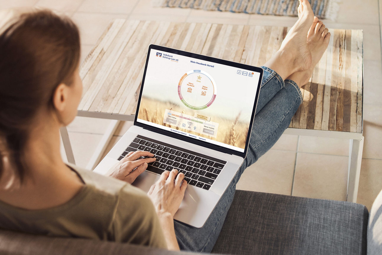 Eine Frau sitzt mit gekreuzten Beinen auf einer Couch und benutzt einen Laptop.