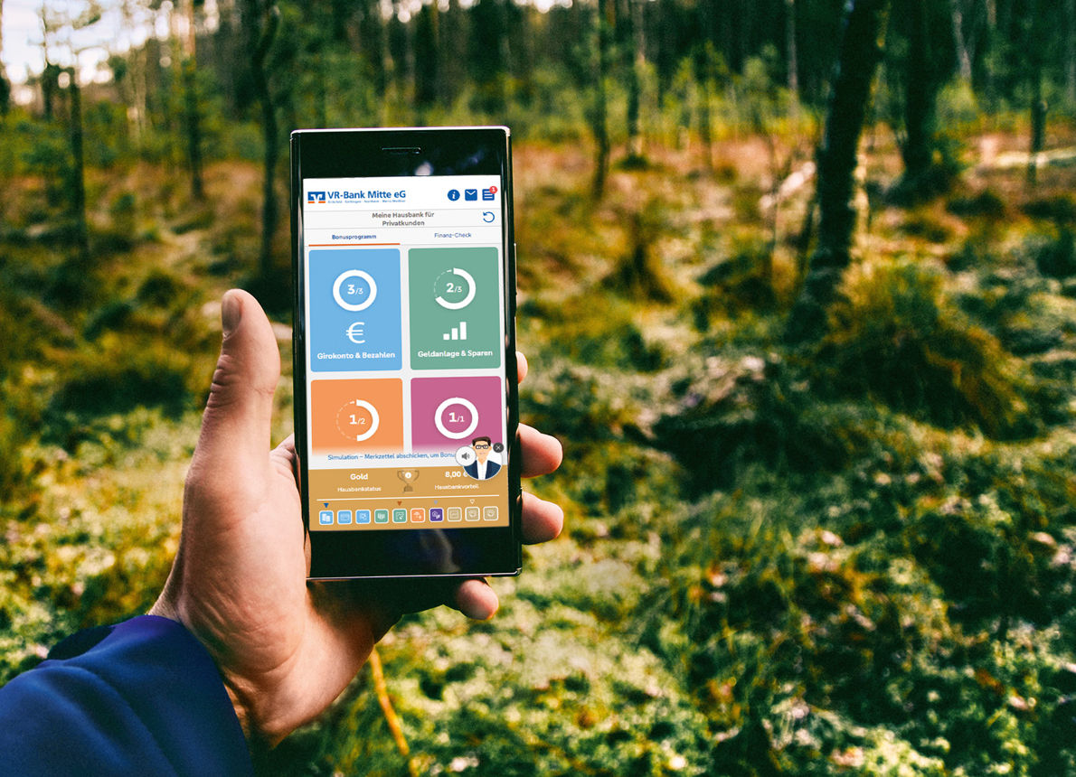 Handy haltend in der Natur mit der Grafik vom Hausbankmodell