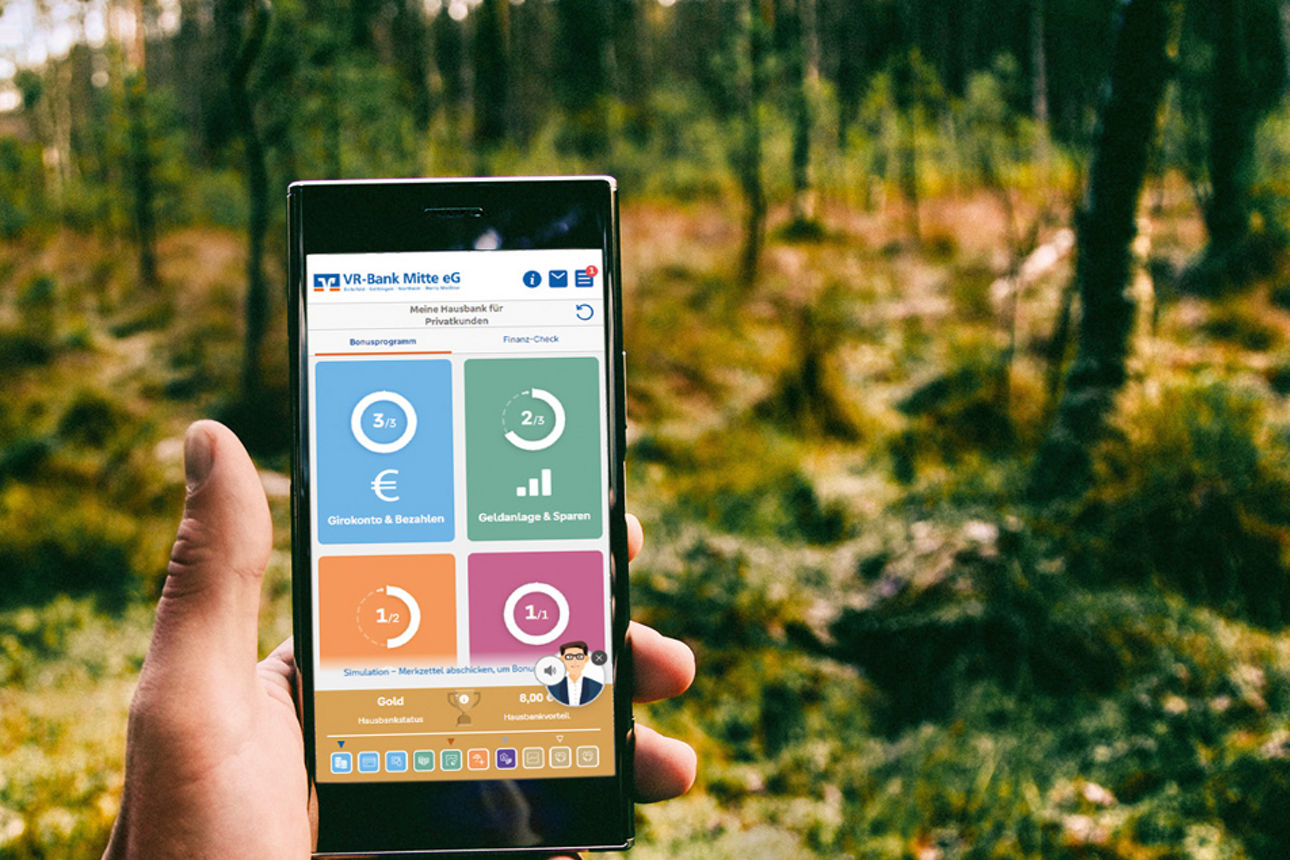 Handy haltend in der Natur mit der Grafik vom Hausbankmodell