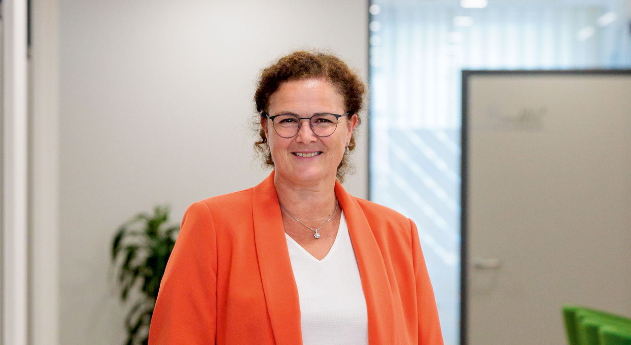 Frau mit dunklen Haaren mit orangem Blazer
