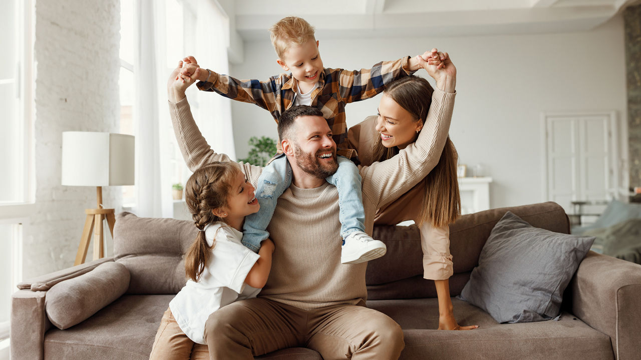 Familie mit zwei Kindern lacht auf dem Sofa