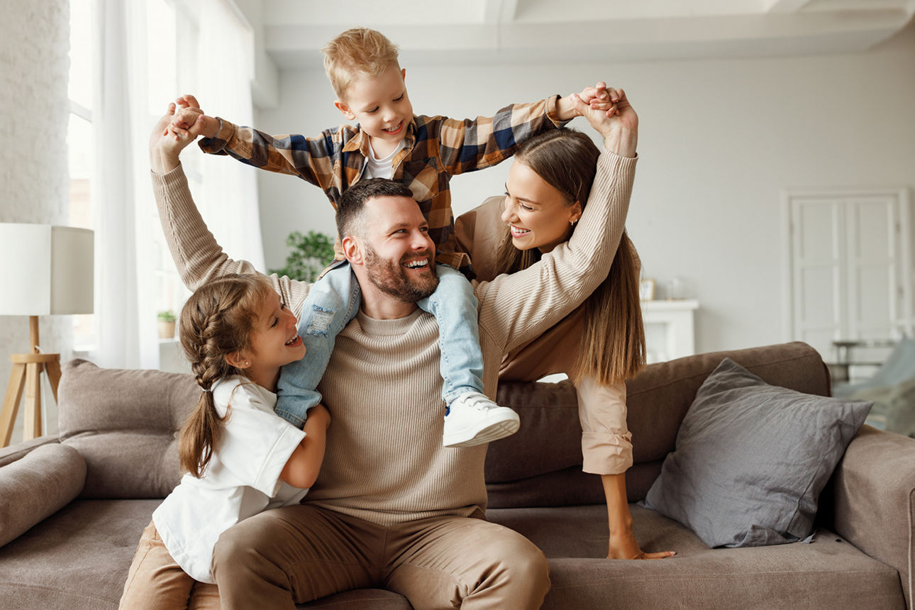 Familie mit zwei Kindern lacht auf dem Sofa