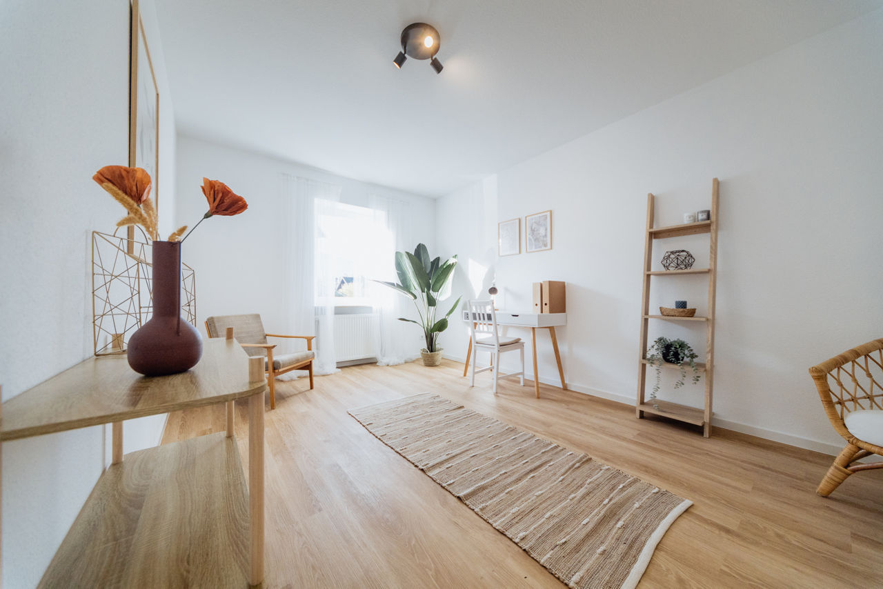 Innenansicht eines modernisierten Wohnraums der HAVANOLA Immobilien GmbH mit heller Farbgestaltung, Holzboden, Sitzmöbeln und funktionalem Arbeitsbereich für zeitgemäßes Wohnen.