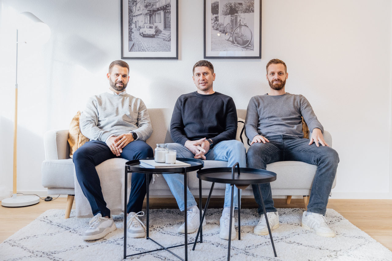 Mehrere Personen sitzen in einem fertig eingerichteten Wohnbereich einer von der HAVANOLA Immobilien GmbH entwickelten Immobilie mit klaren Raumstrukturen und moderner Möblierung.