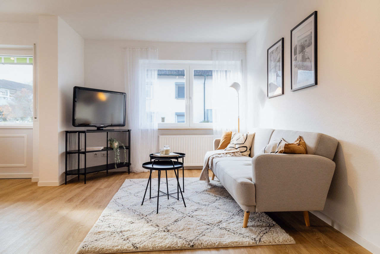 Wohnzimmer einer sanierten Immobilie der HAVANOLA Immobilien GmbH mit Sofa, Teppich, Beistelltischen und TV‑Bereich als Beispiel für ein durchdachtes Wohnkonzept.