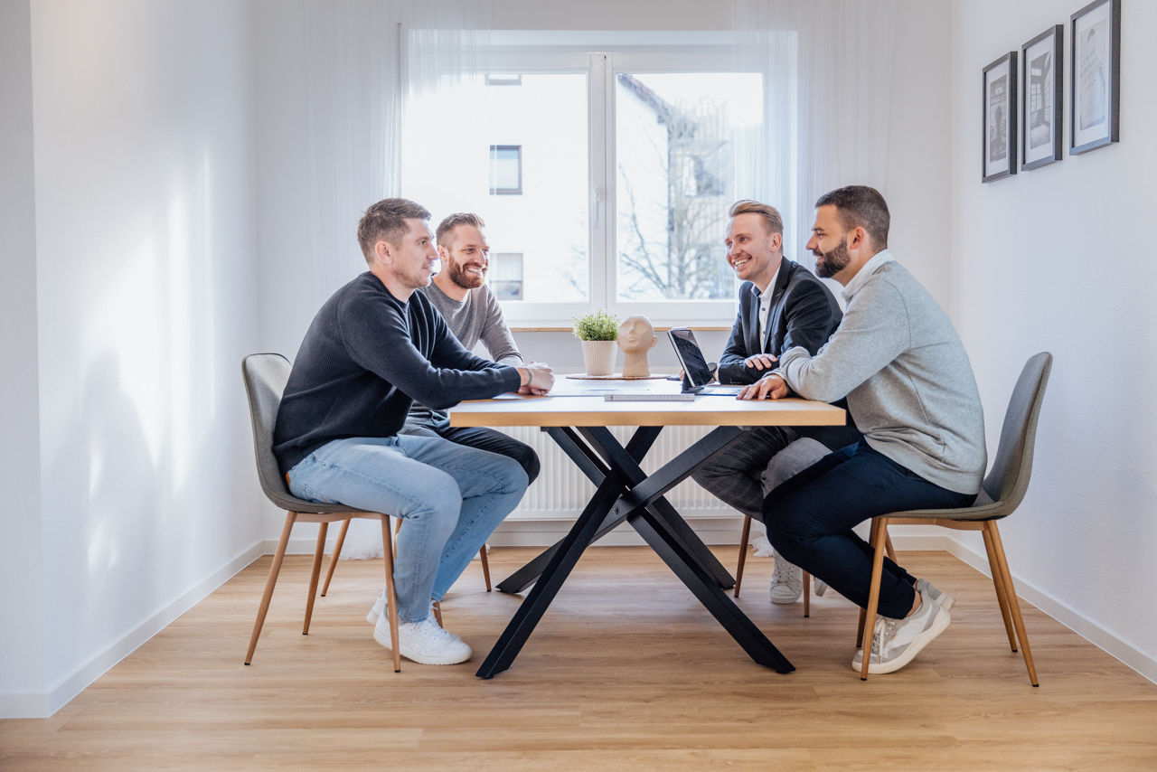 Mehrere Personen sitzen an einem Tisch in einer modernisierten Wohnung der HAVANOLA Immobilien GmbH, die als Raum für Austausch, Planung und Besprechung genutzt wird.