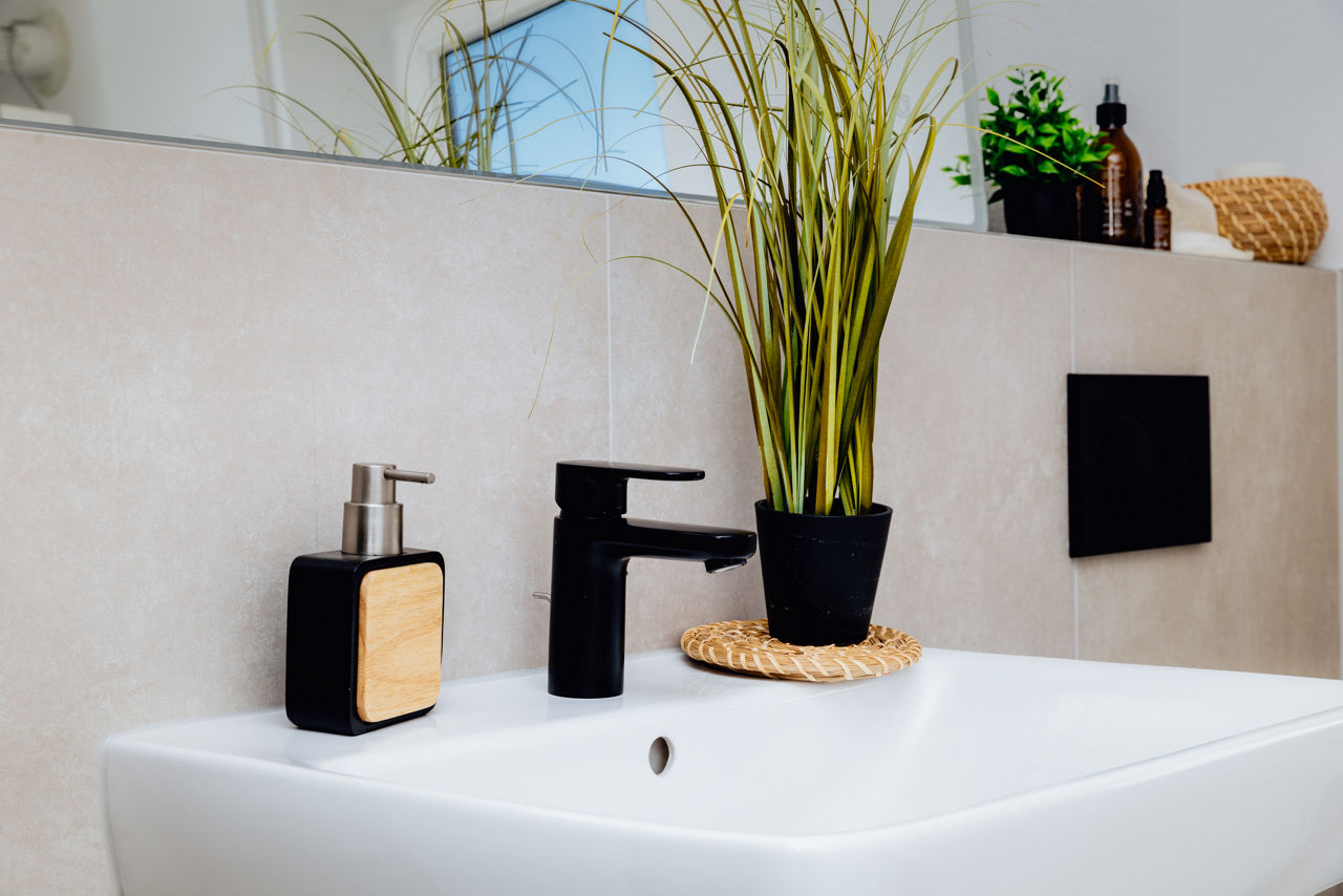 Detailaufnahme eines modernen Waschbeckenbereichs in einer Immobilie der HAVANOLA Immobilien GmbH mit Armatur, Ablageflächen und reduzierten Designelementen.