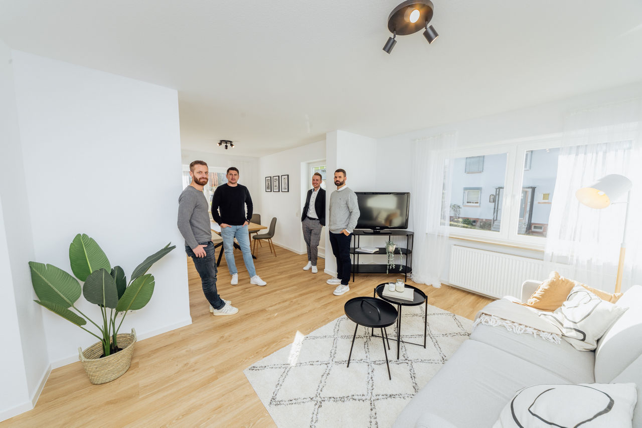 Mehrere Personen stehen in einem offen gestalteten Wohnbereich einer sanierten Immobilie der HAVANOLA Immobilien GmbH, geprägt von moderner Ausstattung und klarer Raumstruktur.