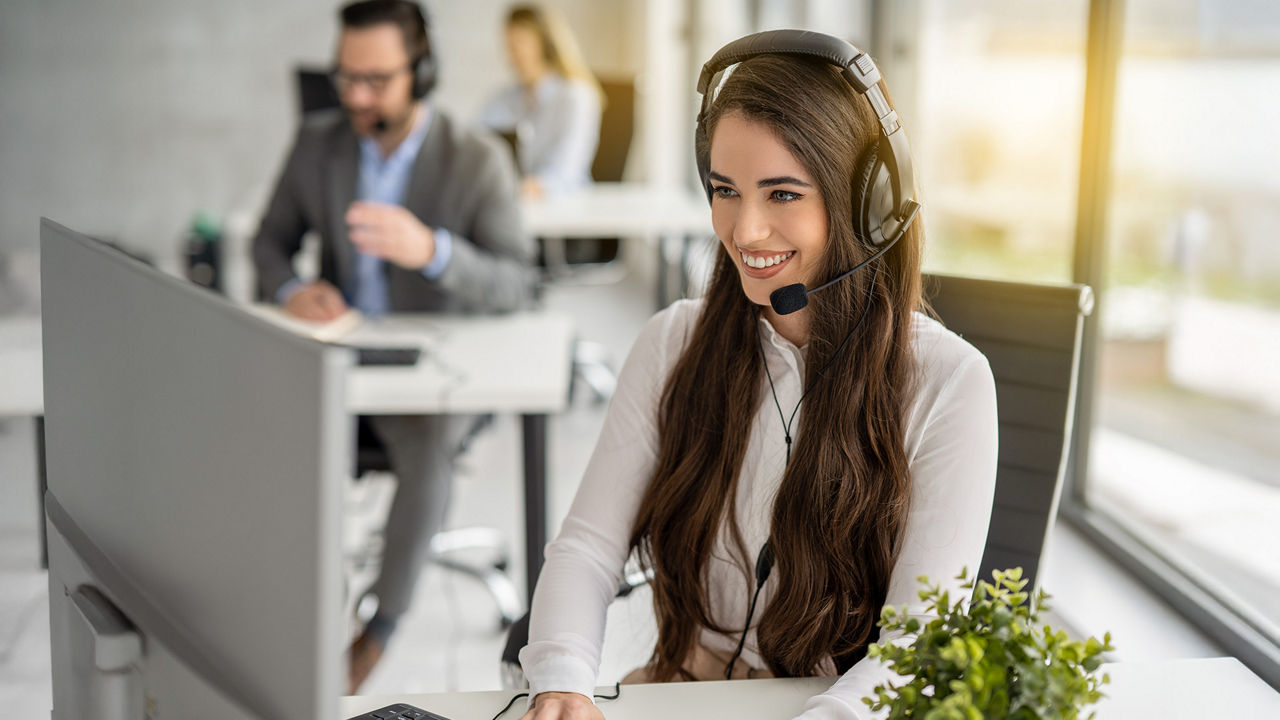 junge Frau im Büro am Schreibtisch mit Headset