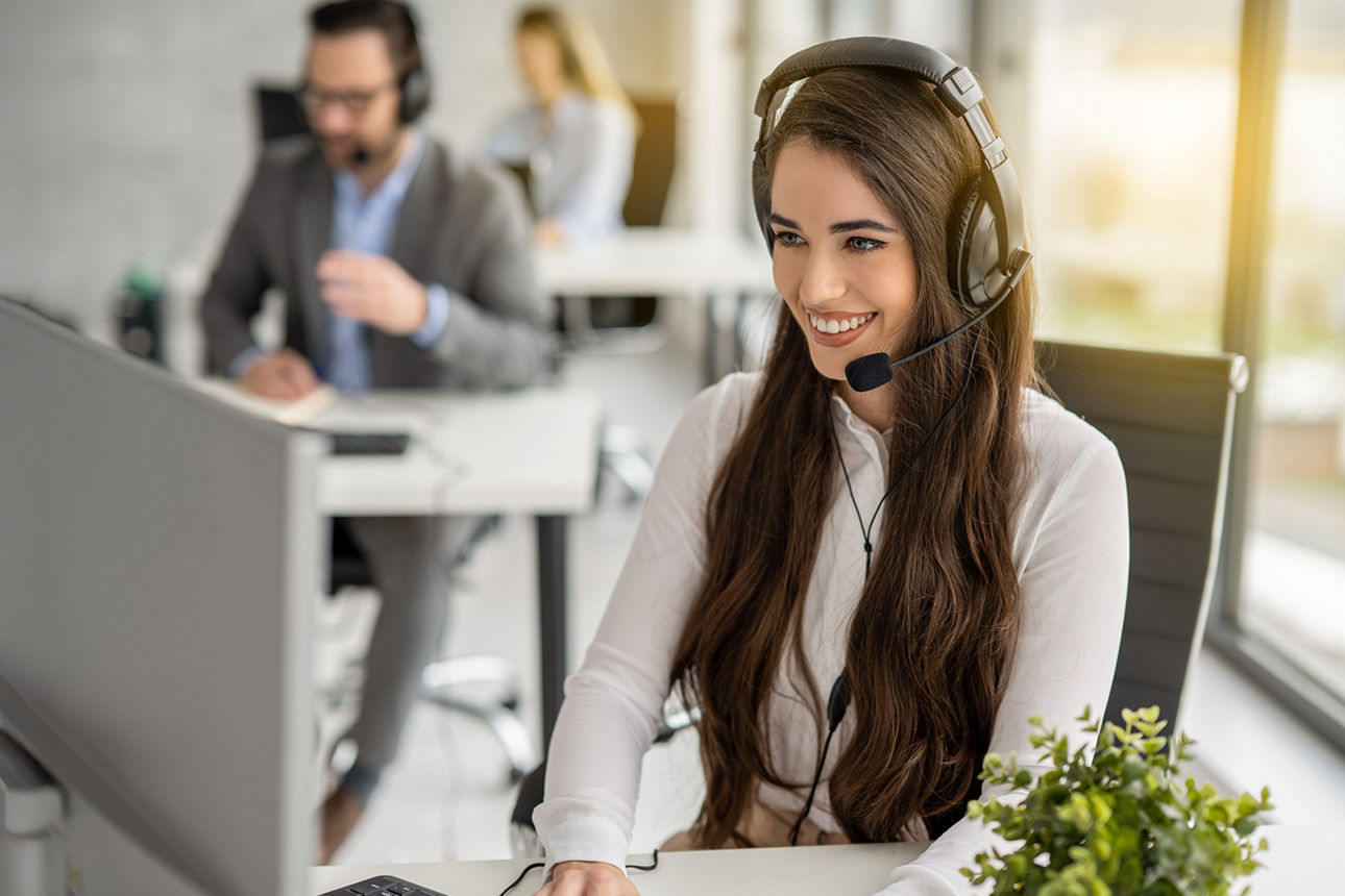 junge Frau im Büro am Schreibtisch mit Headset