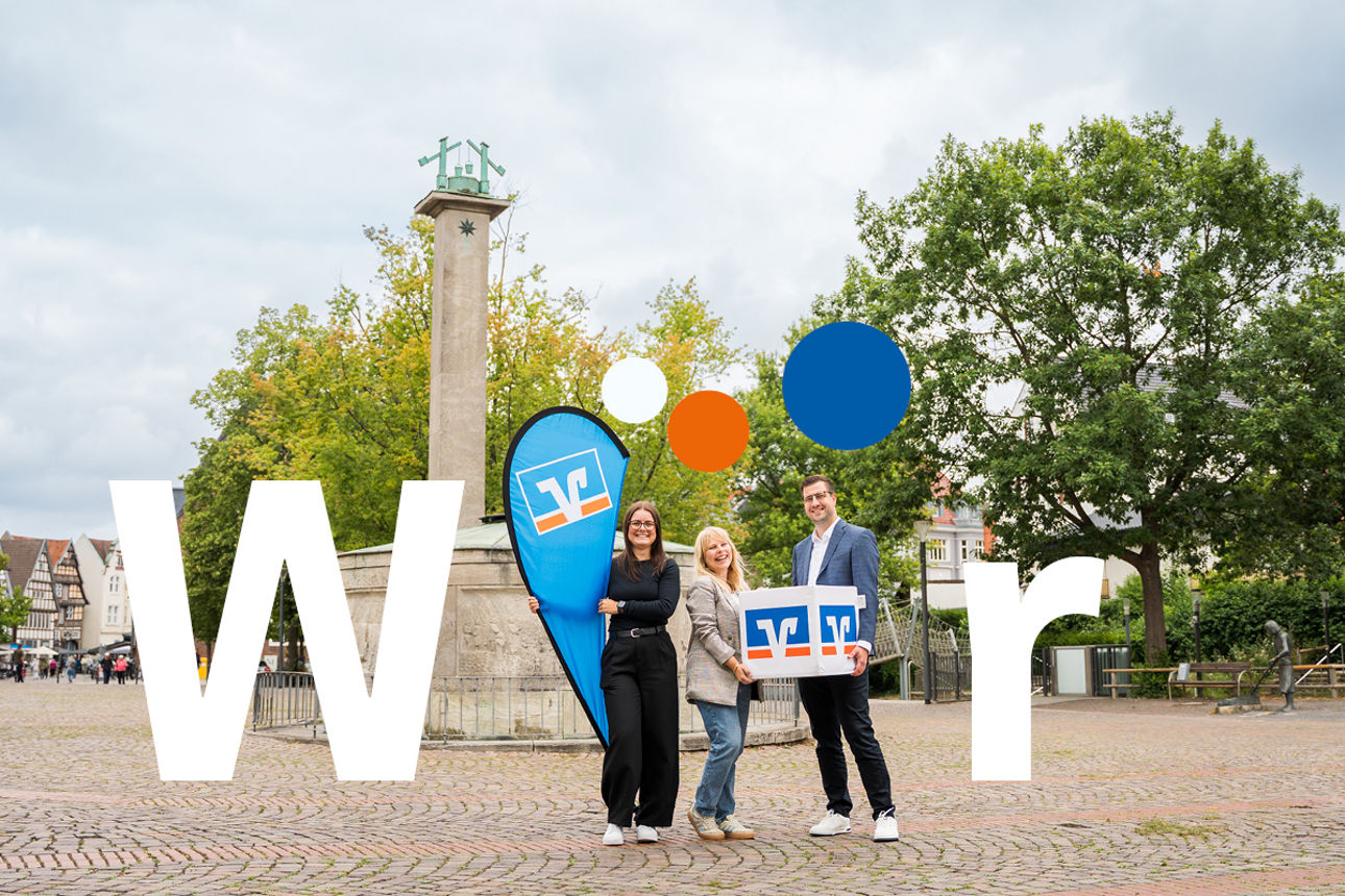 Drei Mitarbeitende tragen Volksbank-Würfel und Flagge durch die Innenstadt von Bad Salzuflen