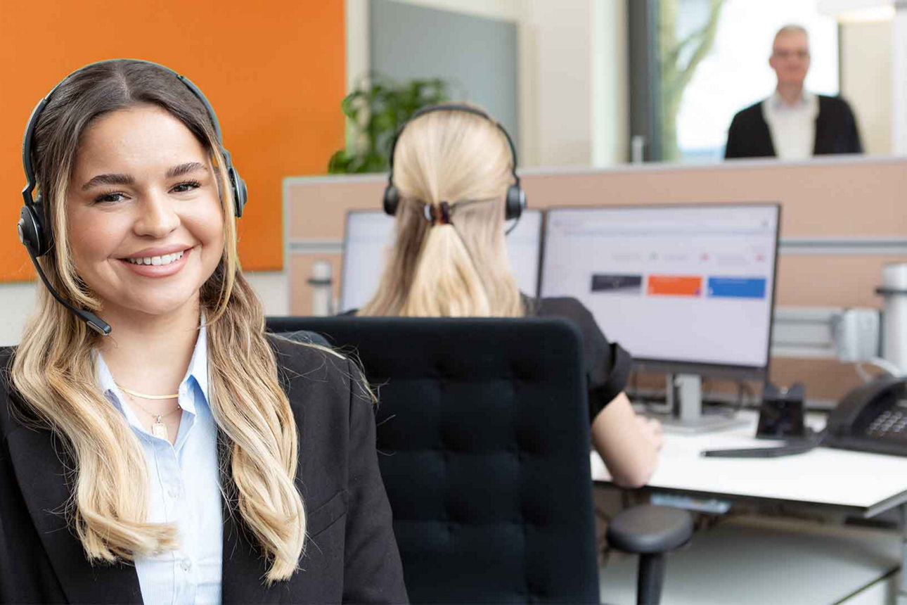 Eine Mitarbeiterin unseres Kundendialogcenters schaut Ihnen entgegen und lächelt.