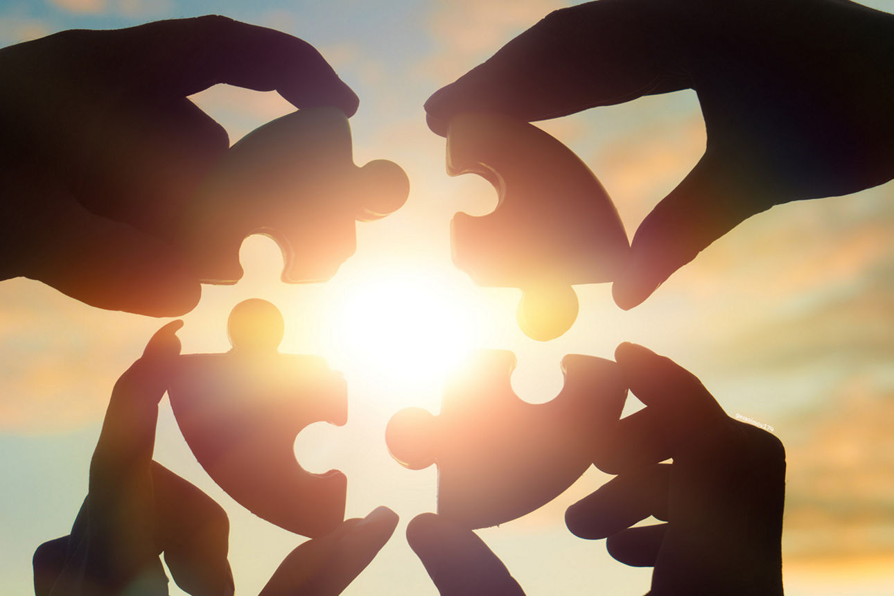 Vier Händ die ein Puzzle zusammen setzen 