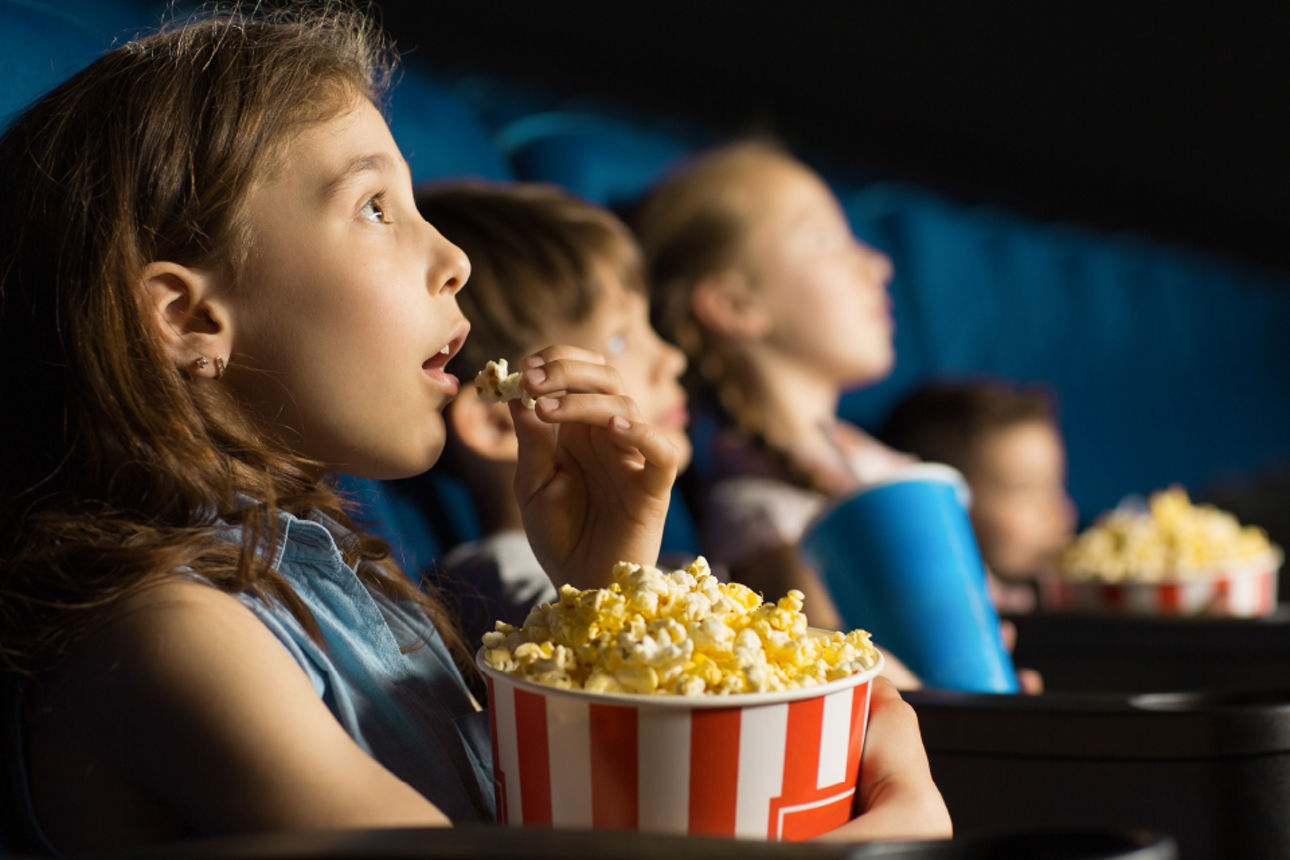 Kinder schauen Kinofilm mit Popcorn an