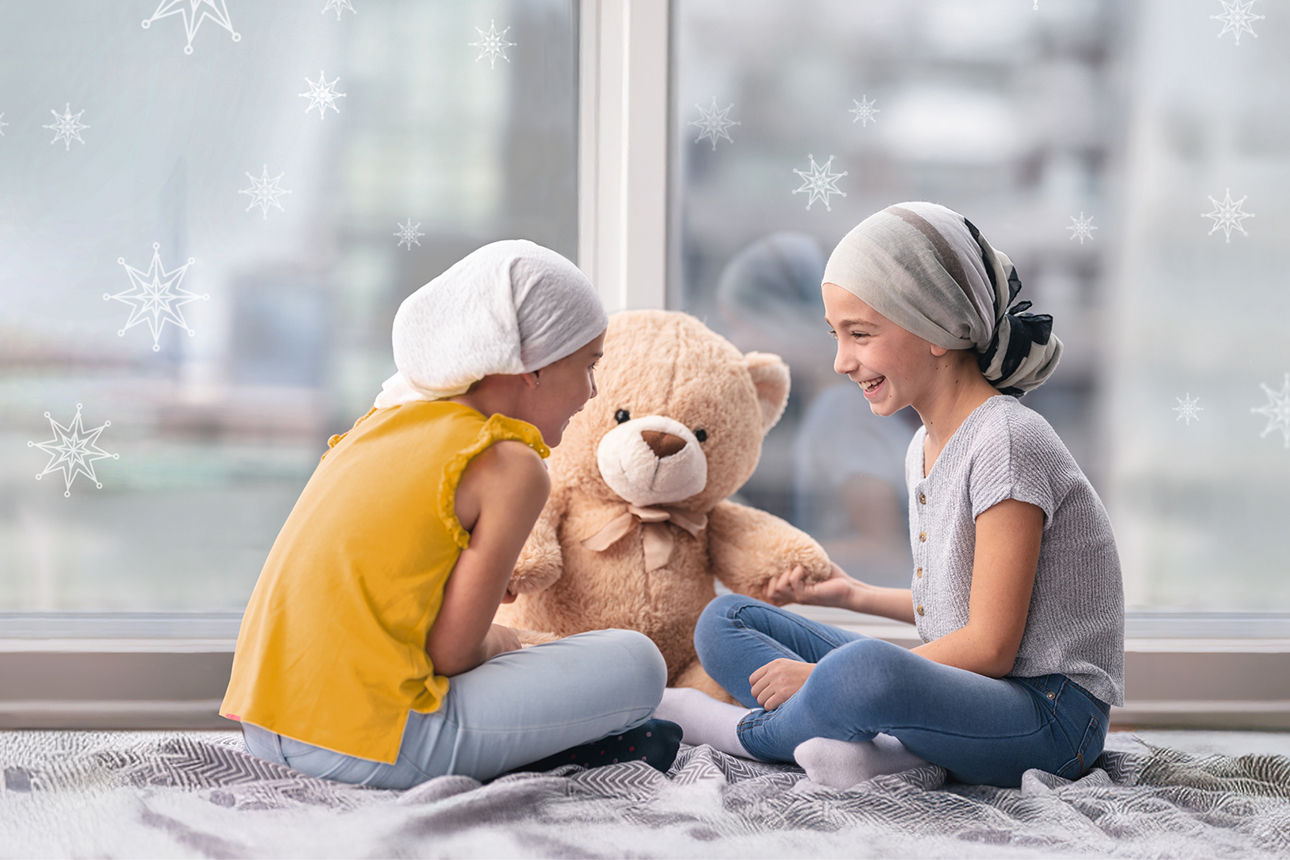 Zwei Kinder sitzen mit einem Teddy auf dem Boden vor einem Fenster