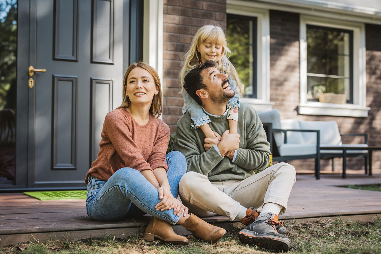 Familie sitzt vor Ihrem neuen Haus