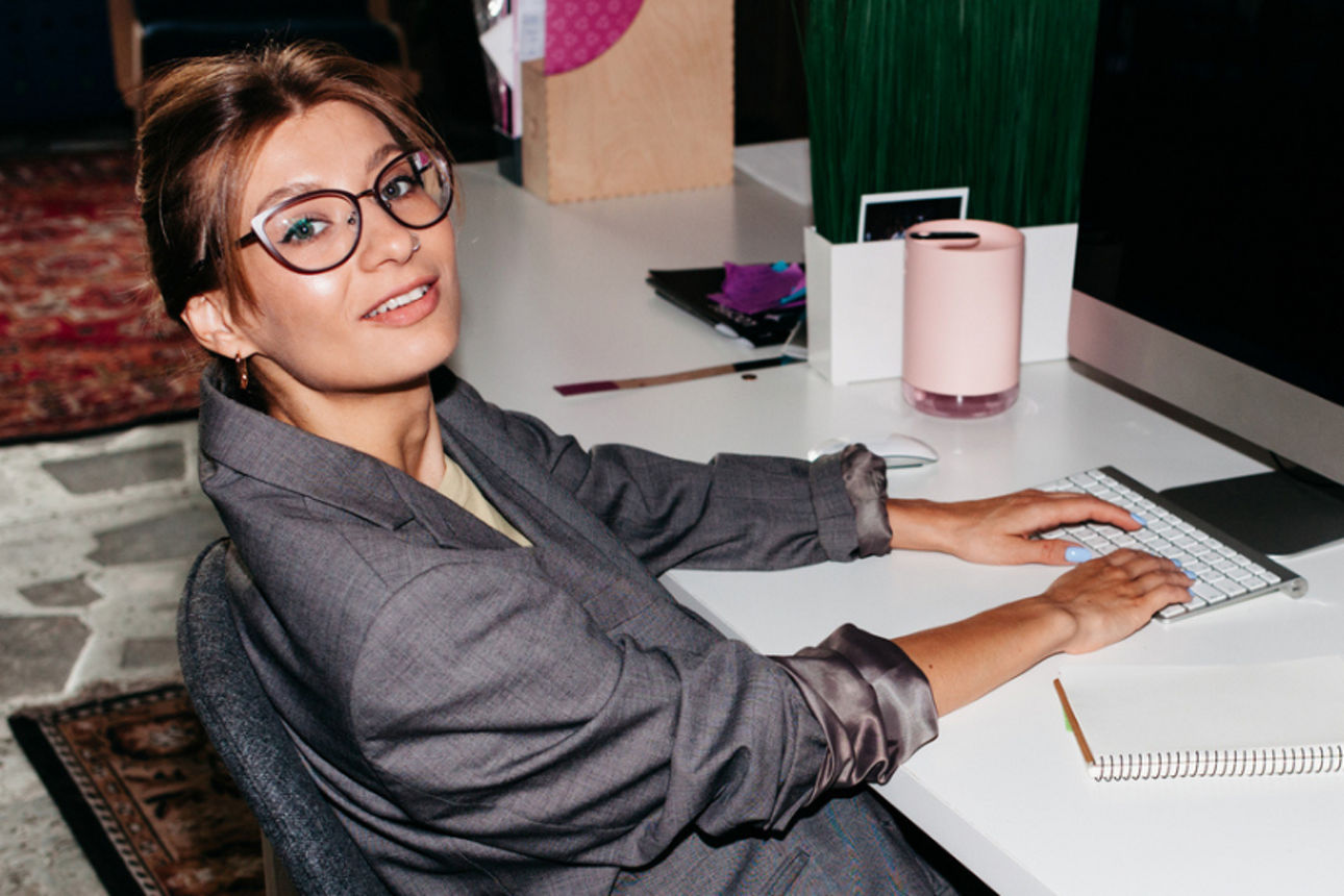 Eine elegant gekleidete junge Frau vor einem Computer