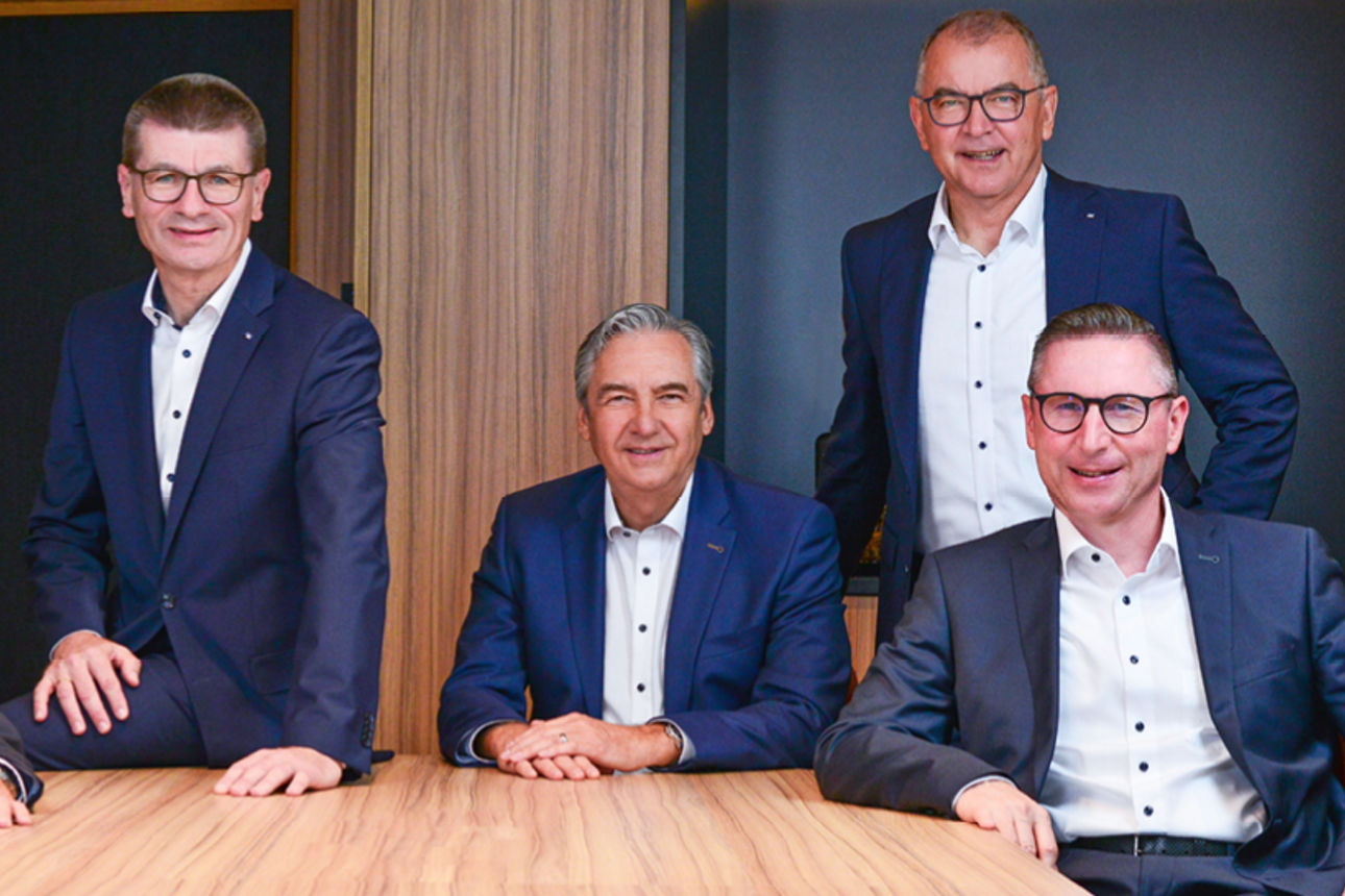 Die Vorstände der VR-Bank Mittelfranken Mitte eG versammelt an einem Tisch blicken in die Kamera