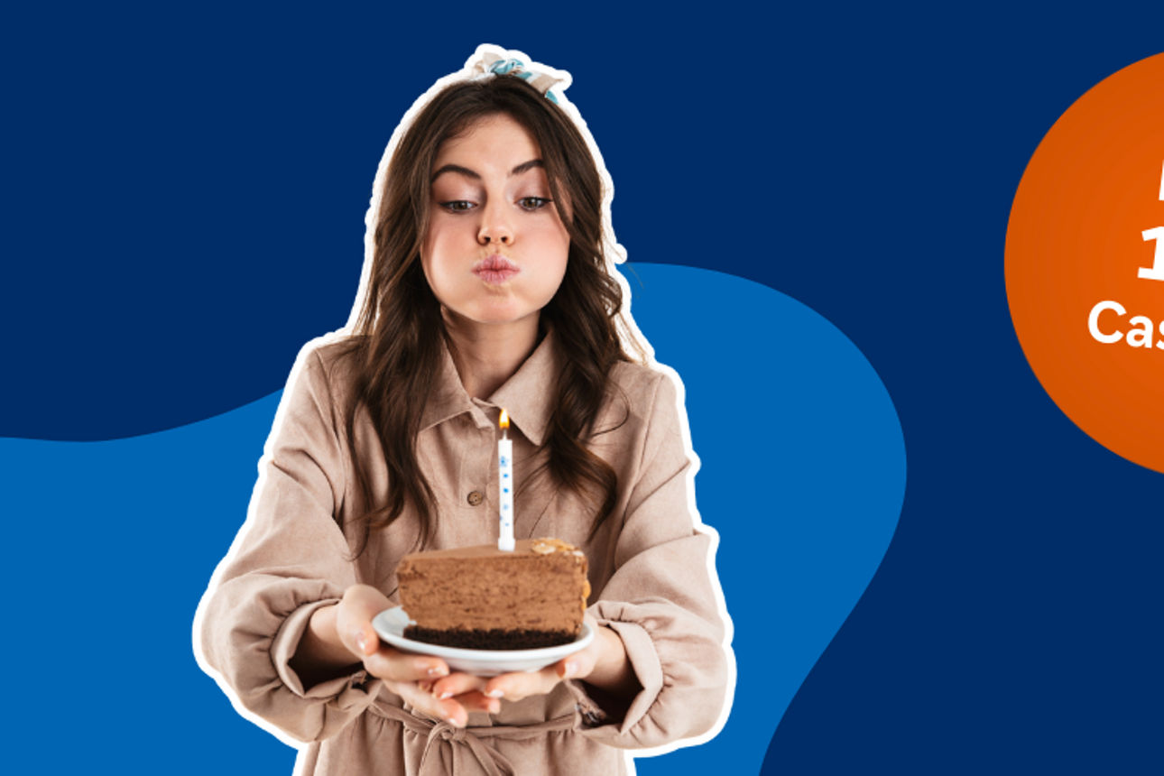 Frau die ein Stück Kuchen auf einem Teller in der Hand hält. Auf dem Kuchen ist eine Kerze die sie versucht auszupusten.