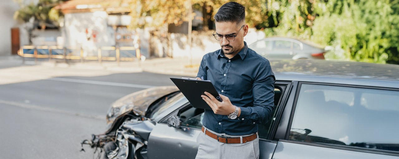 Mann steht mit Klemmbret an sein Auto gelehnt