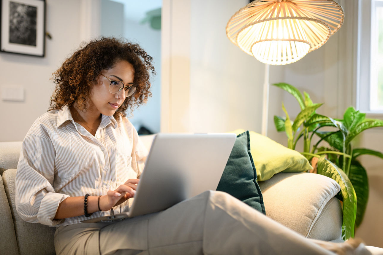 Frau sitzt mit Laptop auf dem Sofa
