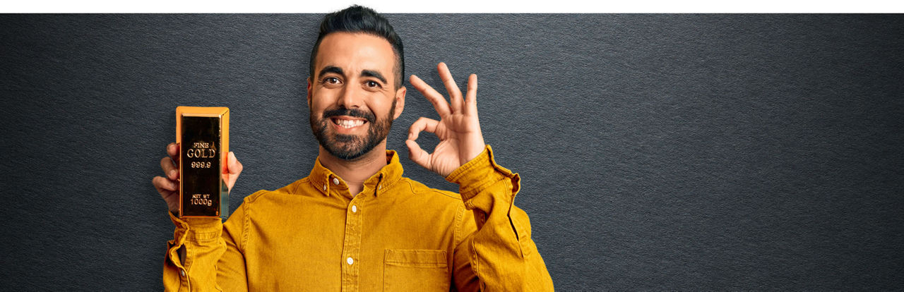 Junger Mann hält einen Goldbarren in der Hand