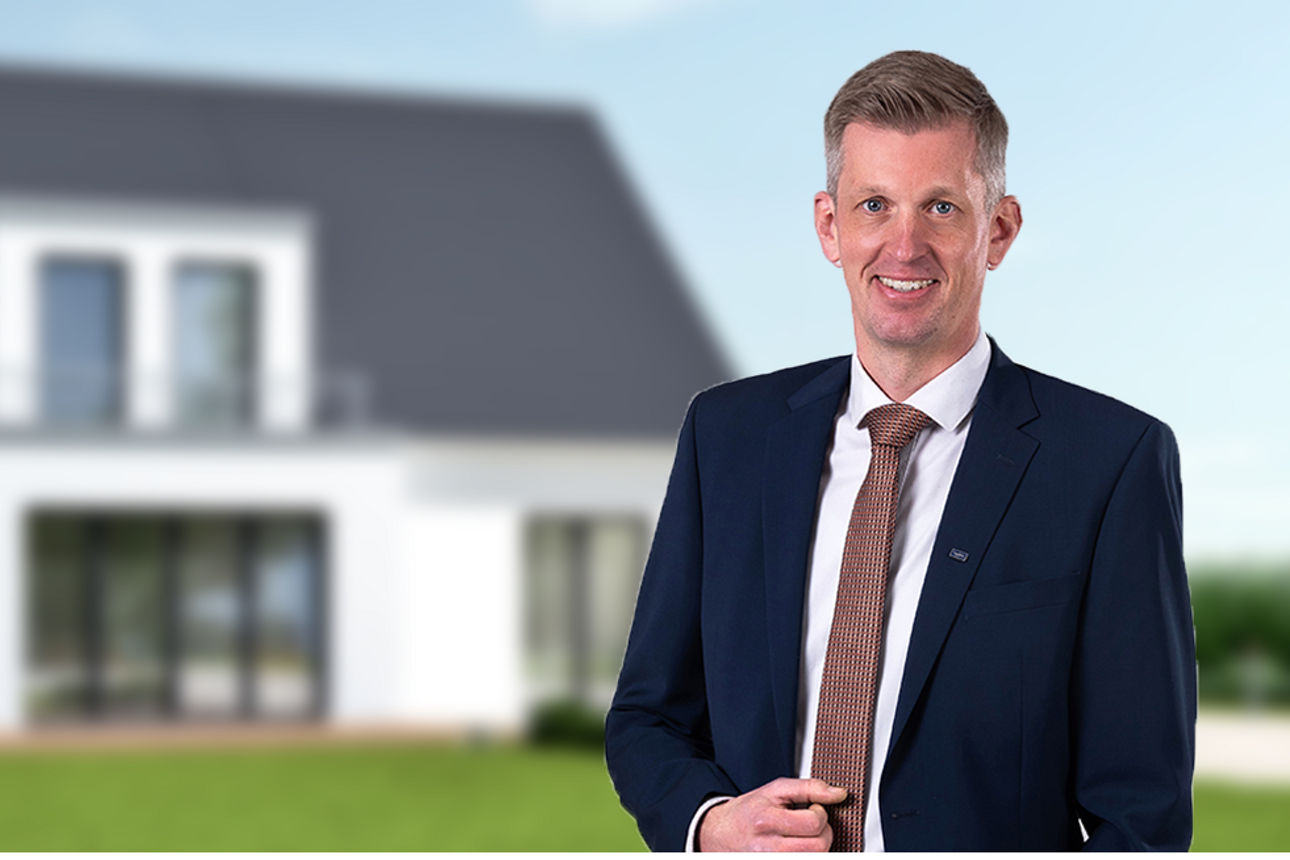 Der Geschäftsführer der NOW-Immo GmbH steht vor einem neuen Haus