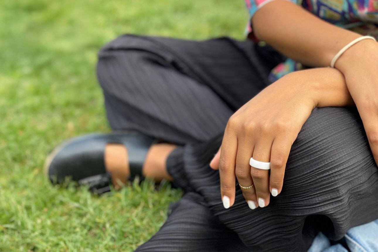 Frau sitzt auf einer Wiese und trägt ein Wearable am Finger