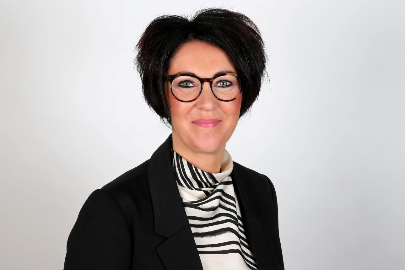 Eine lächelnde Frau schaut in die Kamera.