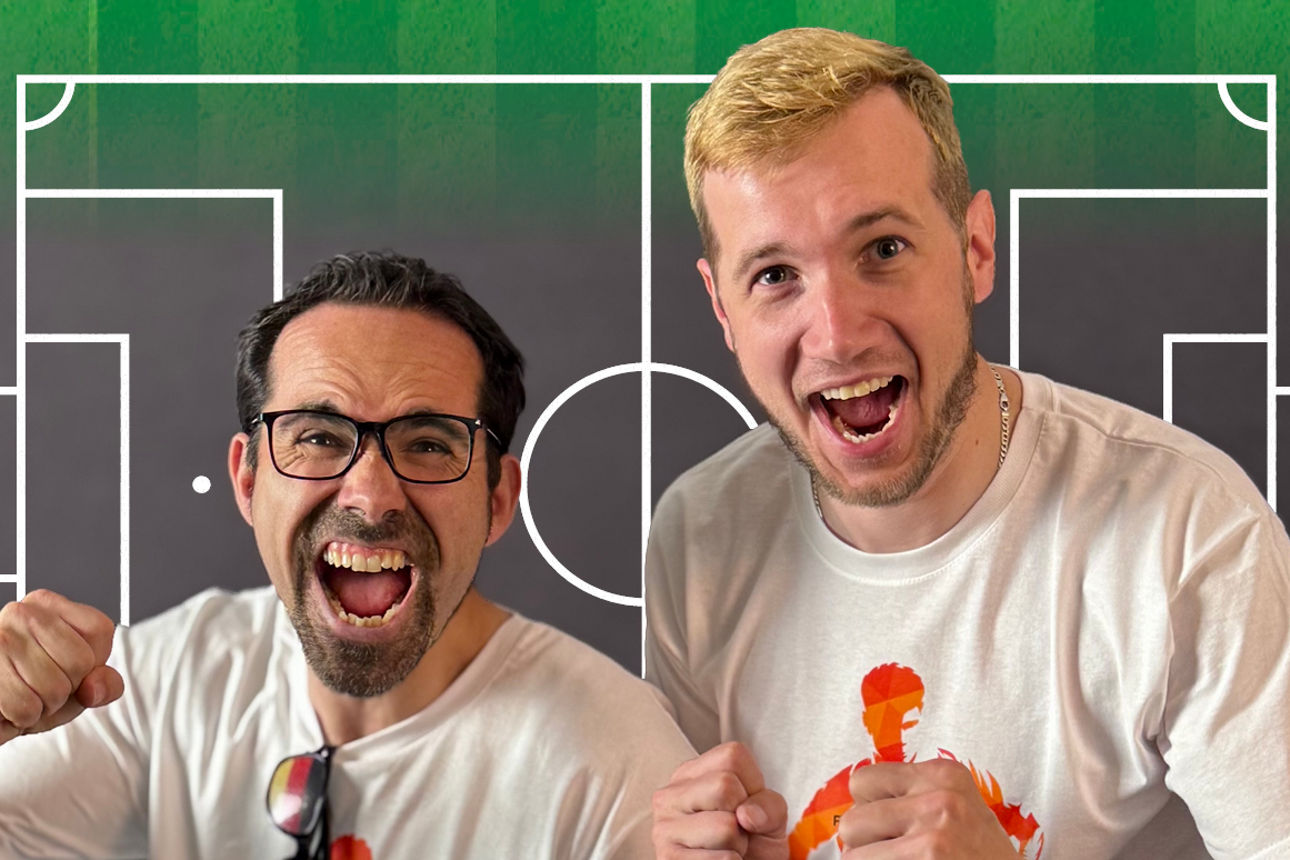 Sie sehen 2 Mitarbeiter, die mit WM-Utensilien nebeneinander stehen.
