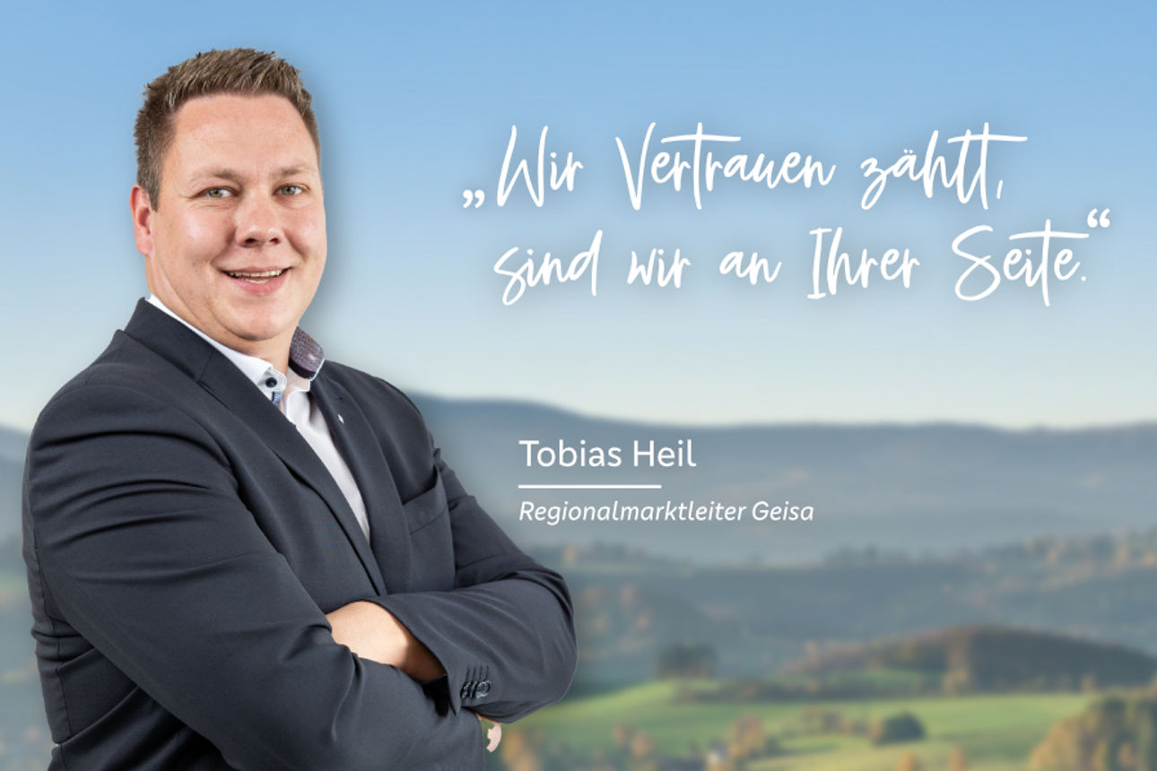 Bereichsleiter PrivatkundenTobias Heil lachend vor einer Berglandschaft mit verschränkten Armen