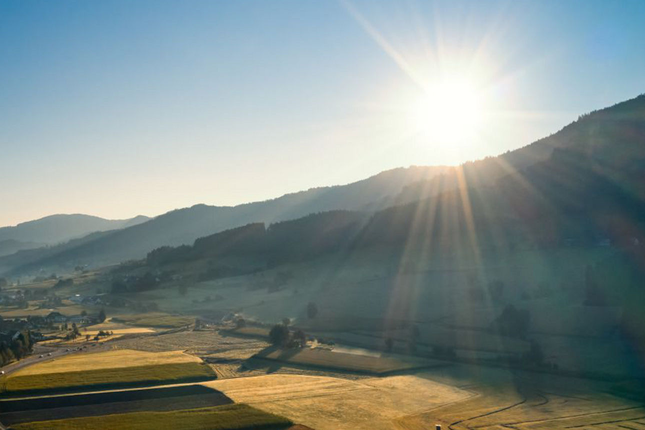 Landschaft mit Sonne am blauen Himmel