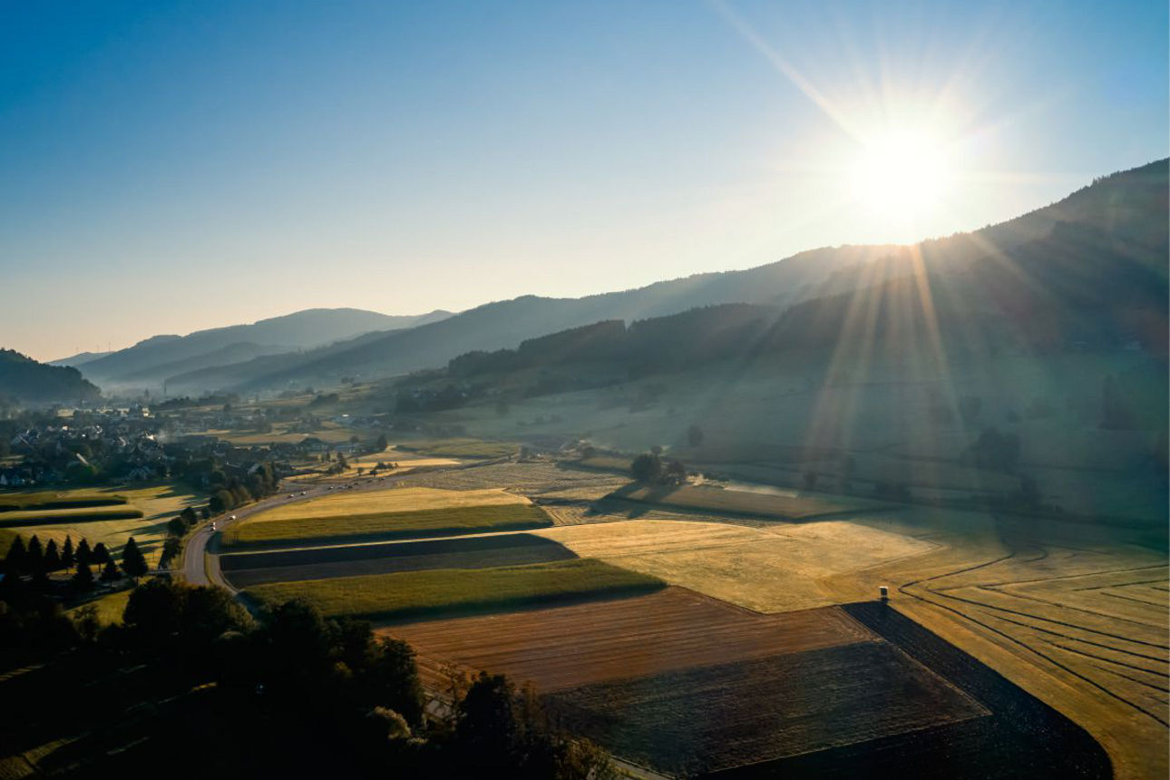 Landschaft mit Sonne am blauen Himmel